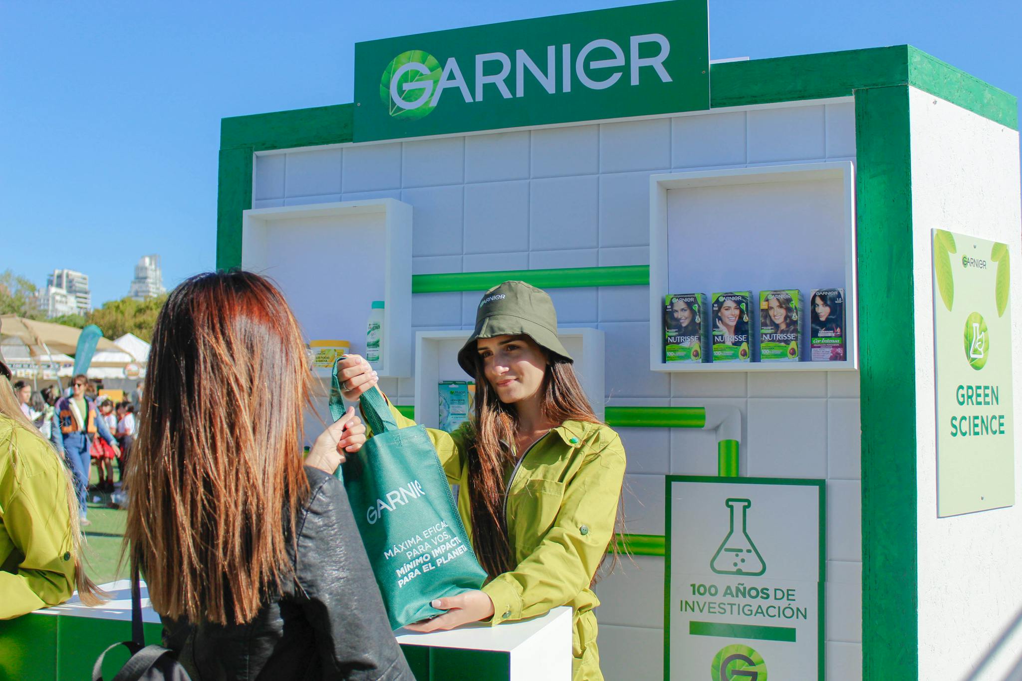 Garnier event with women distributing branded bags at an outdoor stall.